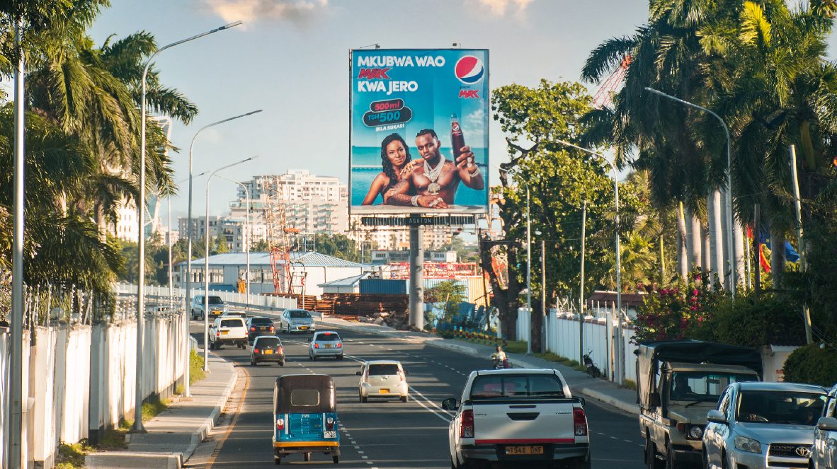 A Pepsi billboard between palm trees on a main road in Dar es Salaam